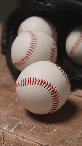 Vertical-Video-Close-Up-Studio-Baseball-Still-Life-With-Balls-And-Catchers-Mitt-On-Wooden-Floor-6